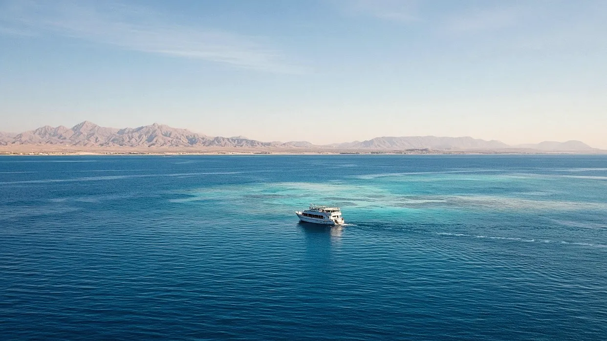 White dive boat on turquoise water with the Sinai mountains behind