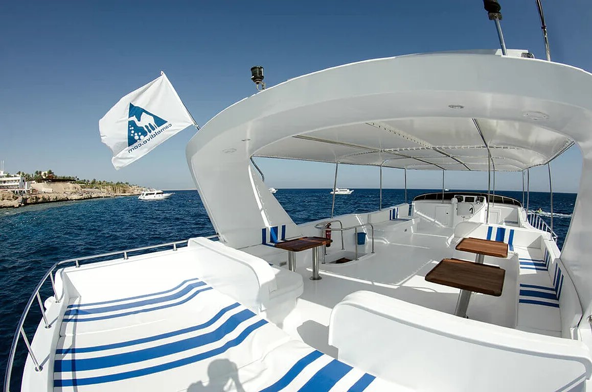 Upper deck of a white day boat at sea, with the Sharm coast behind
